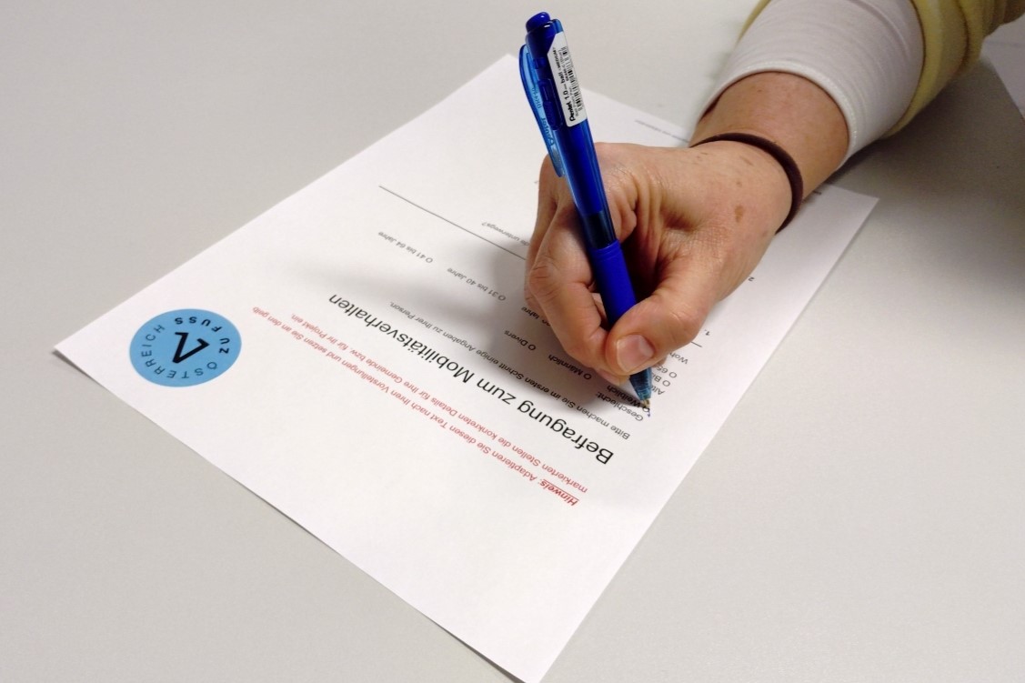 Eine Hand füllt einen Umfragebogen mit Kuli aus