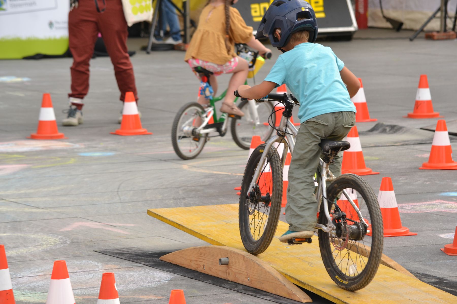 Kind am fahrrad mit Helm fährt Parcour entlang, gerade über eine Rampe