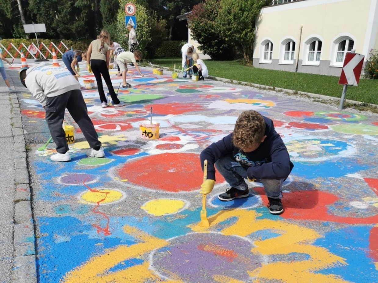 Kinder bemalen die Straße mit bunten Blumen