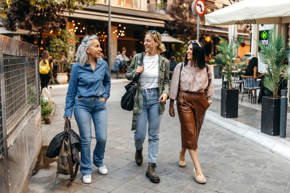 Drei Frauen gehen zu Fuß durch die Innenstadt und reden miteinander